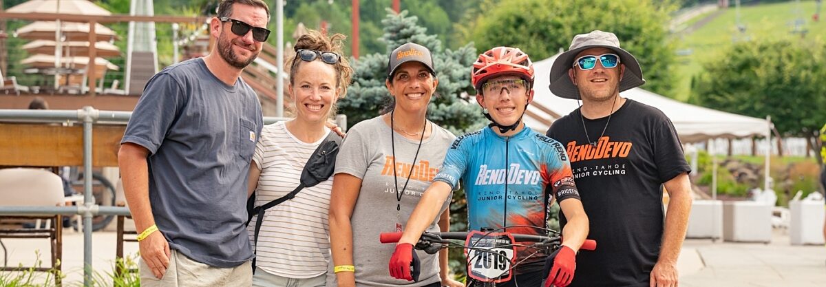 Family and friends gathered, smiling around a junior rider.