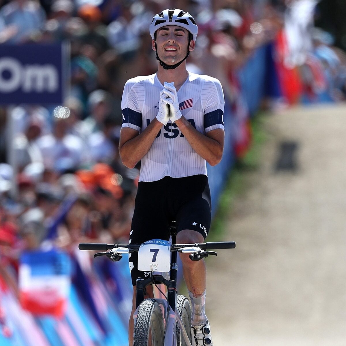 Men's mountain bike finals with rider holding his hands in a praise position over his heart.