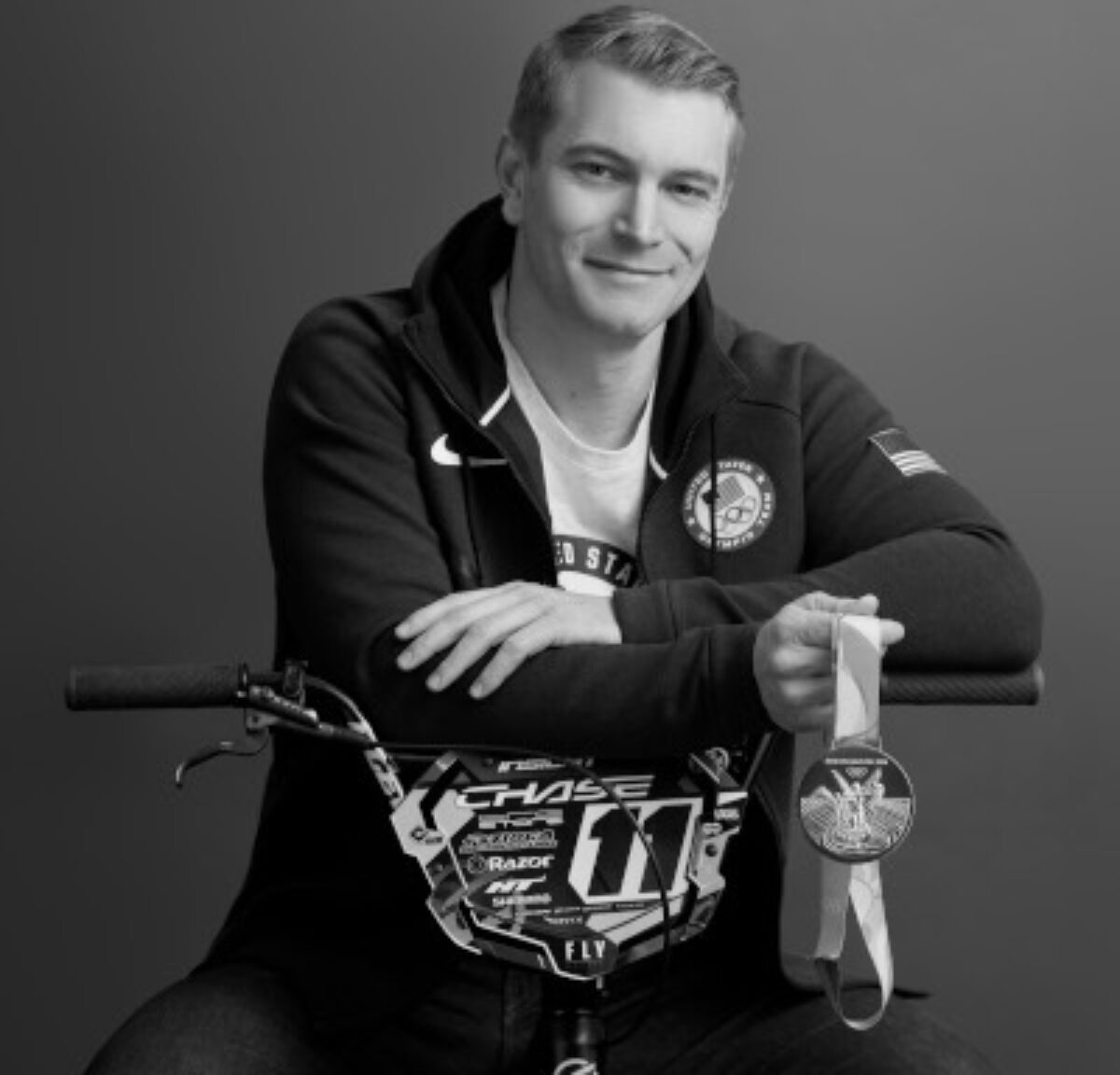 Conor Fields posing for a photo while sitting on a BMX bike and holding a medal