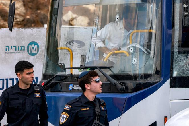 Two Israeli policemen walk past the windshield of a bus, riddled with bullet holes, at the scene of a shooting at the Ramot road junction in Israeli-annexed east Jerusalem on September 8, 2025.