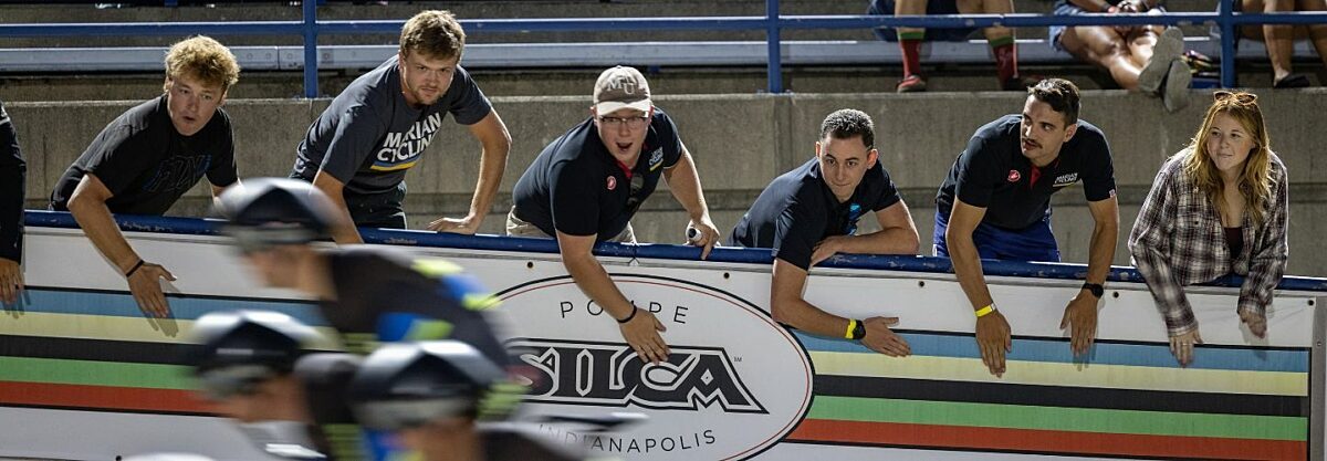 Fans banging on the side of the track to cheer on the track racers.