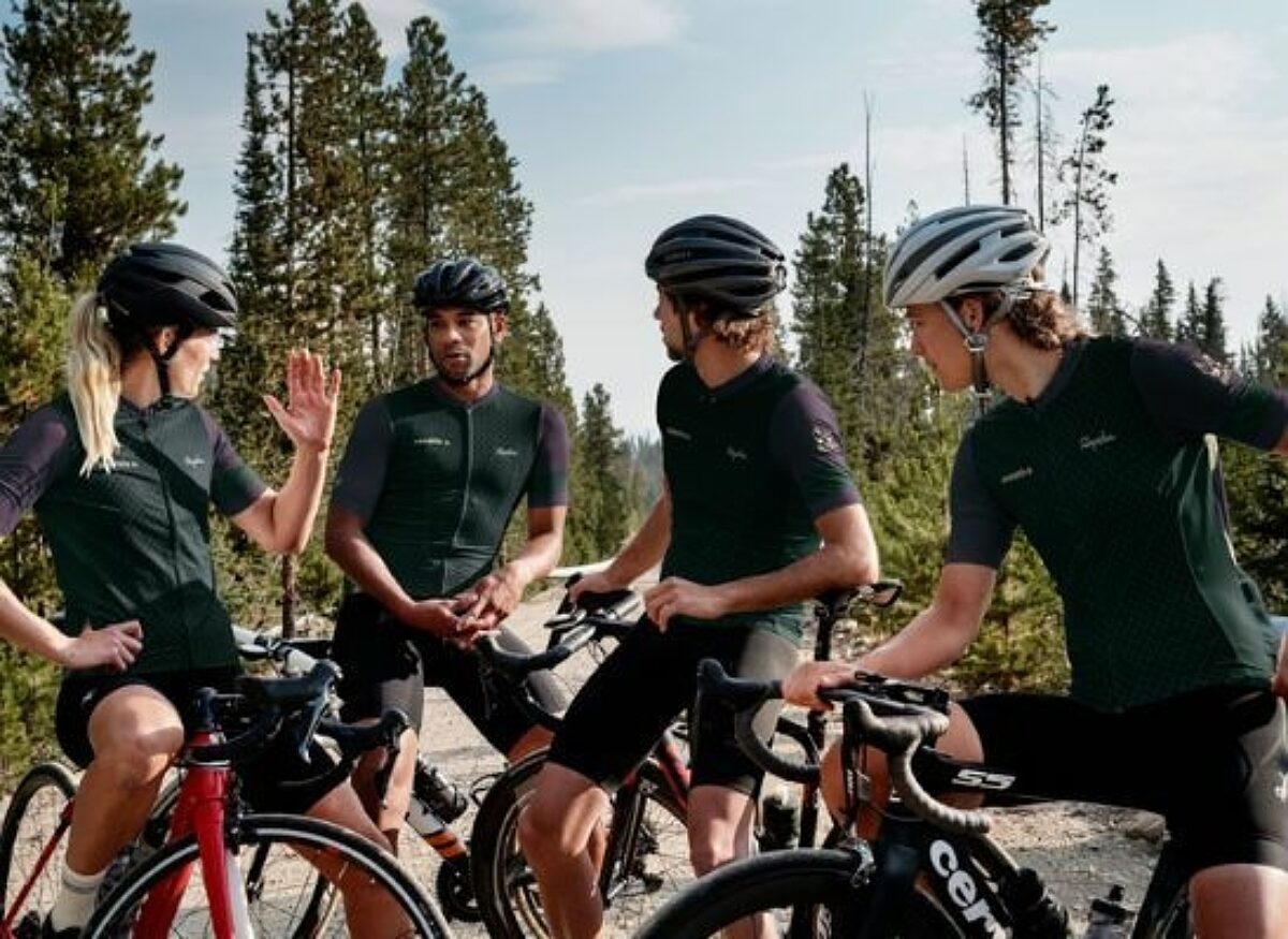 Group of bikers stopped, conversing on the side of the trail.
