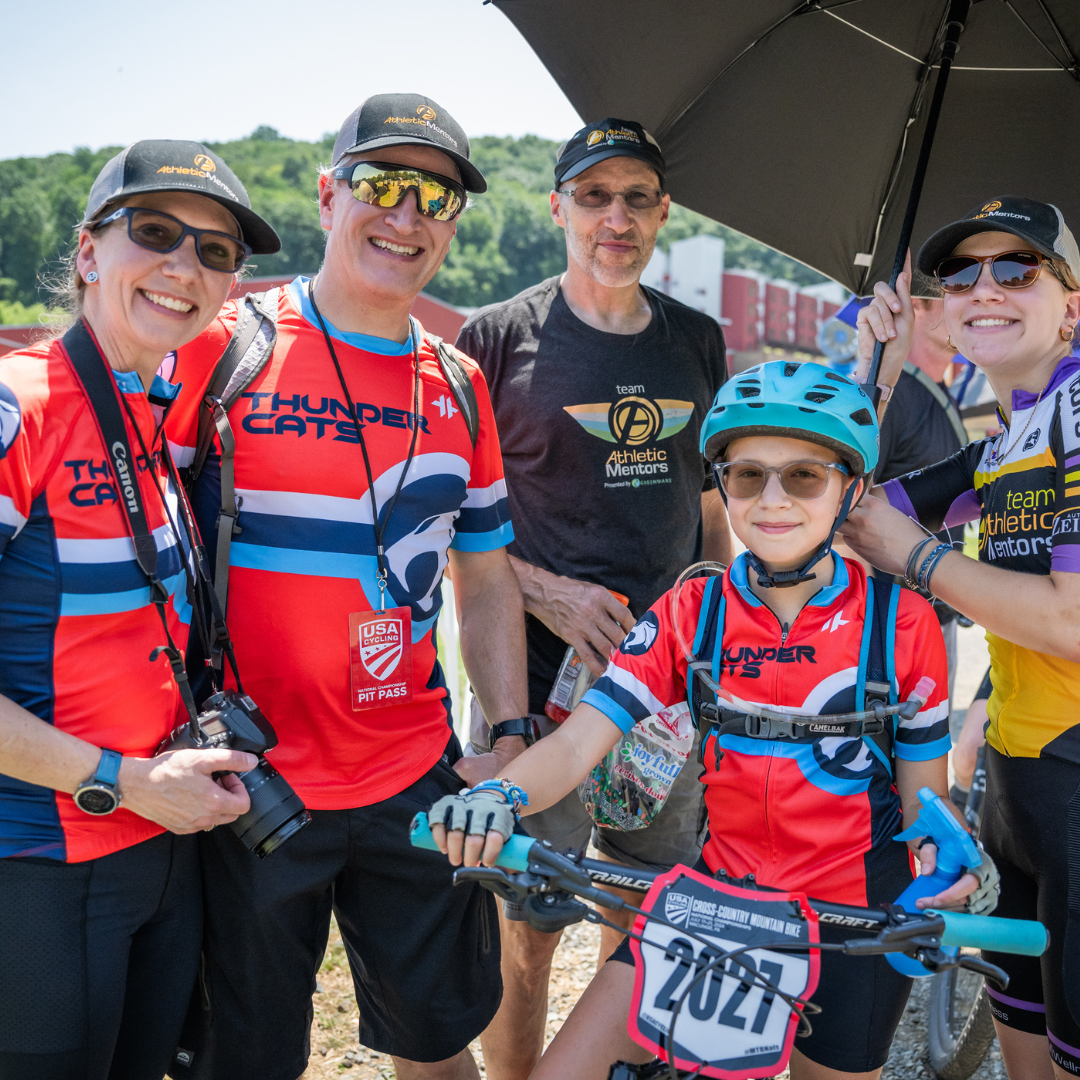 Junior racer on bike surrounded by older racers.