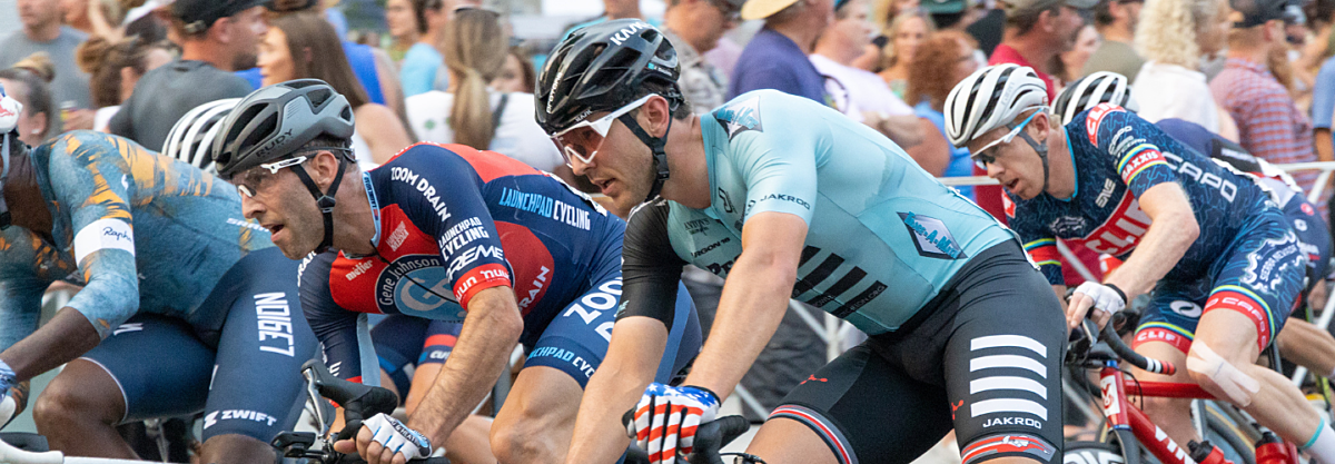 Road racers going through a corner being watched by fans.